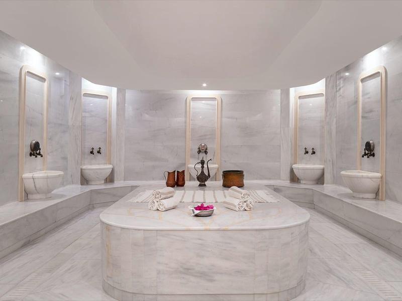 Un lussuoso hammam turco con lavandini e colonne in marmo.
