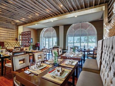 Intérieur d'un restaurant élégant avec murs en bois, grandes fenêtres et tables joliment dressées.