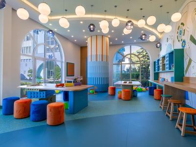 Colorful modern hotel lounge with round seating, large windows, and hanging globe lights.