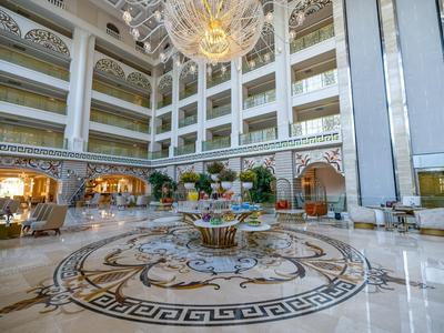 Spacious hotel lobby with marble floor, central floral arrangement, and elegant chandelier.