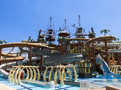 Water park featuring a pirate ship, water slides, and pool under a blue sky.