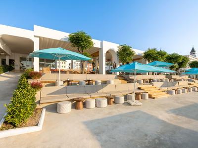 Modern hotel area with shaded seating and clear white buildings.