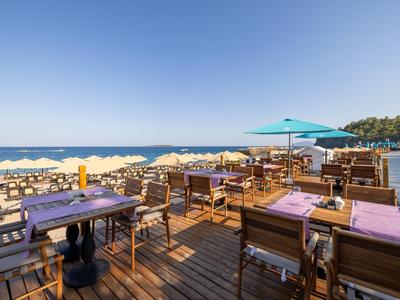 Offenes Restaurant mit Holzboden und Meerblick bei klarem Himmel.