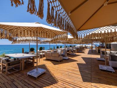 Open beach area with wooden floor, covered seating, and sea view.