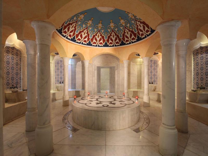 Innenraum eines runden, prächtig verzierten türkischen Bades mit Mosaiken und Säulen.