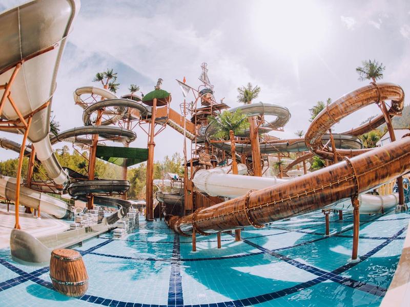 Großer bunter Wasserrutschenpark mit mehreren Spiralen und türkisblauem Schwimmbecken.