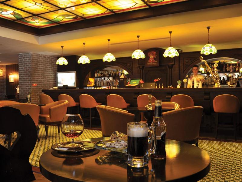 Elegante Bar mit warmem Licht, runden Tischen, bequemen Stühlen und beleuchtetem Deckendekor.