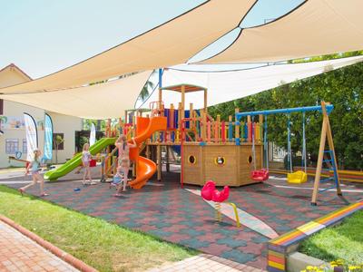 Parco giochi colorato con scivolo, altalene e struttura per arrampicata sotto tende da sole