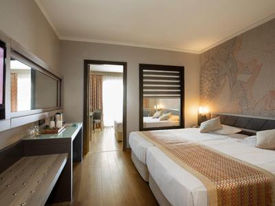 Camera d'hotel moderna con due letti, scrivania, grande specchio e pavimento in legno.