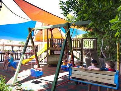 Bambini giocano su un'altalena colorata all'aperto con tende da sole.