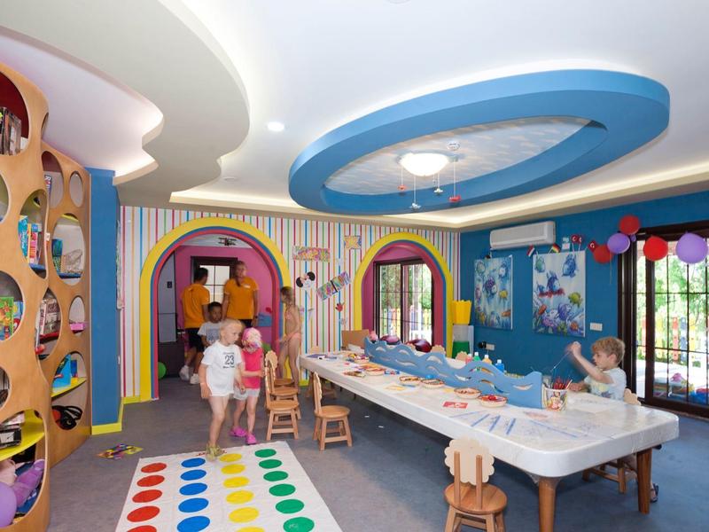 Sala giochi colorata per bambini con tavolo, tappeto da gioco e decorazioni allegre in un hotel.