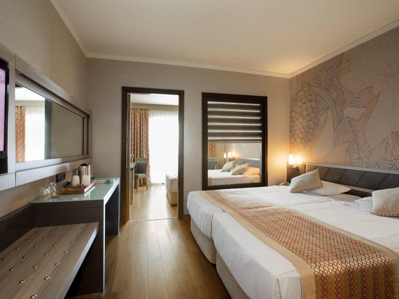 Camera d'hotel moderna con due letti, scrivania, grande specchio e pavimento in legno.