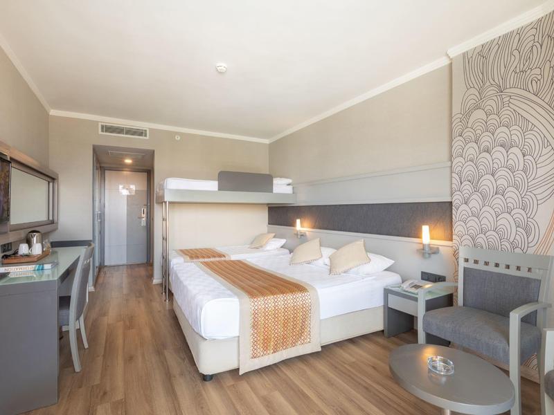 Camera d'hotel moderna con due letti, scrivania, TV e design decorativo sulla parete.