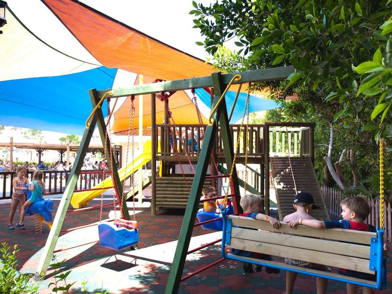 Bambini giocano su un'altalena colorata all'aperto con tende da sole.