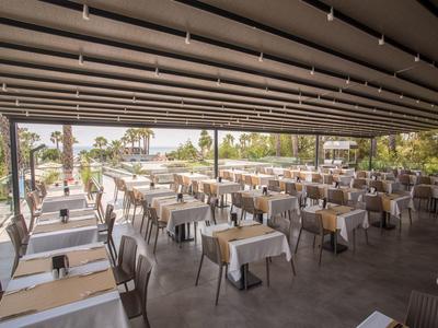 Grande area esterna coperta di un ristorante con molti tavoli e sedie apparecchiati.