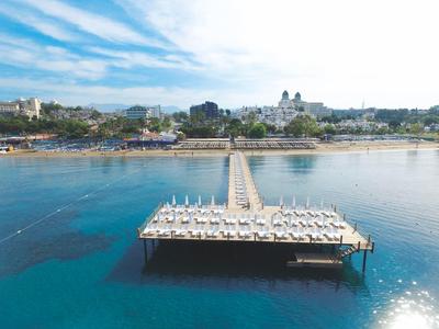 Lunga passerella con lettini sull'acqua calma davanti a una città costiera.