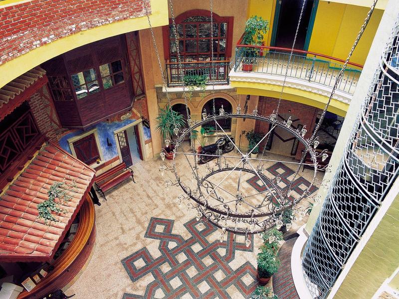 Vista dall'alto di un cortile interno con muri gialli, lampade e motivi decorativi.