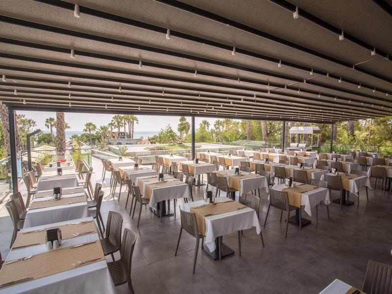 Grande area esterna coperta di un ristorante con molti tavoli e sedie apparecchiati.