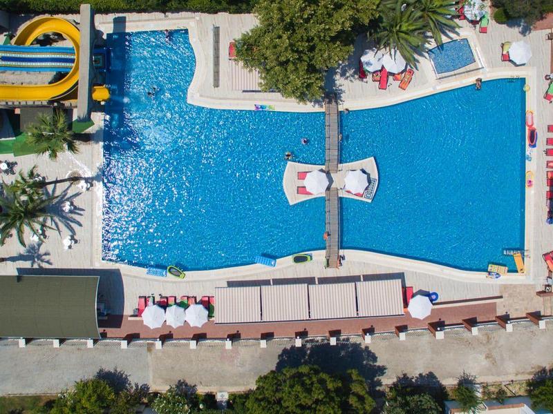 Veduta aerea di una piscina rettangolare con ombrelloni e lettini in un hotel.