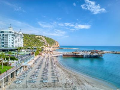 Strand mit Liegen am ruhigen Meer neben einem Hotel unter blauem Himmel mit Wolken.