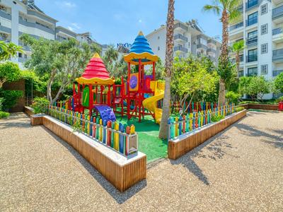 Bunter Kinderspielplatz mit Rutschen und Türmen in einem Hotelhof mit umliegenden Wohngebäuden.