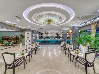 Eleganter Hotellobby mit stilvollen Stühlen, Kronleuchter und Bar im Hintergrund.