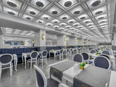 Großer Hotel-Speisesaal mit blauen Stühlen und grauen Tischen unter einer strukturierten Decke.