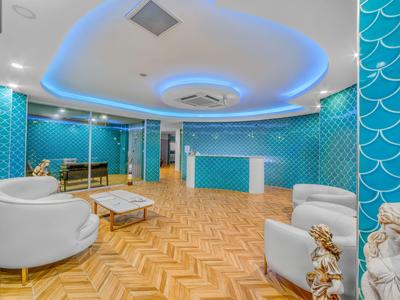 Modern gestaltete Hotellobby mit blauen Wandfliesen, weißen Sesseln und Holzboden.