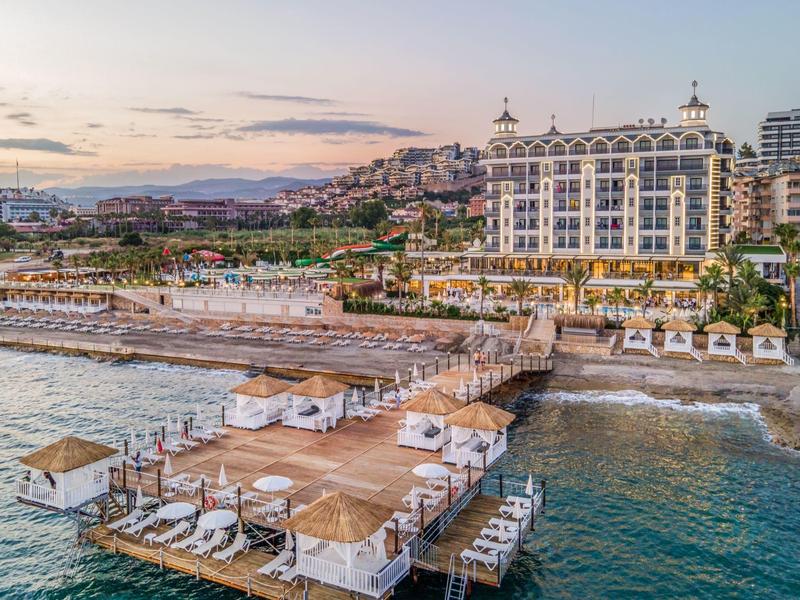 Hôtel de luxe en bord de mer avec piscine, transats et terrasse sur la mer.