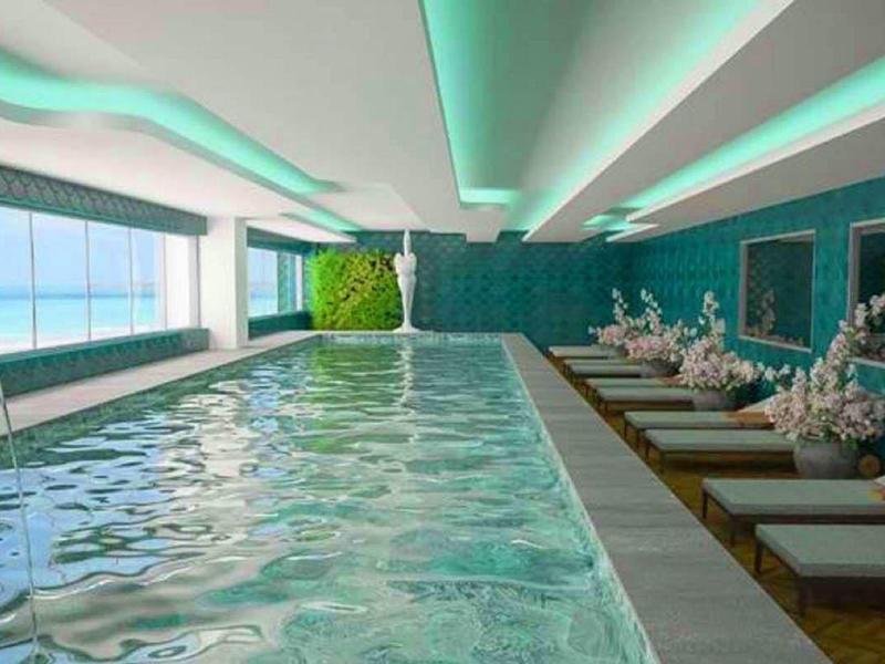 Piscine intérieure moderne avec chaises longues et plantes dans un espace bien-être lumineux et élégant.