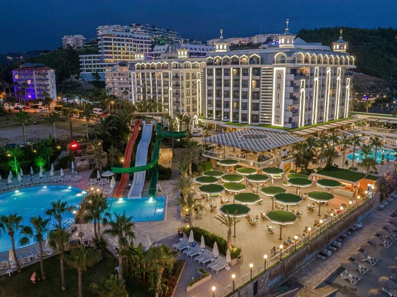 Grand complexe hôtelier avec piscine et de nombreux parasols sur la plage la nuit.