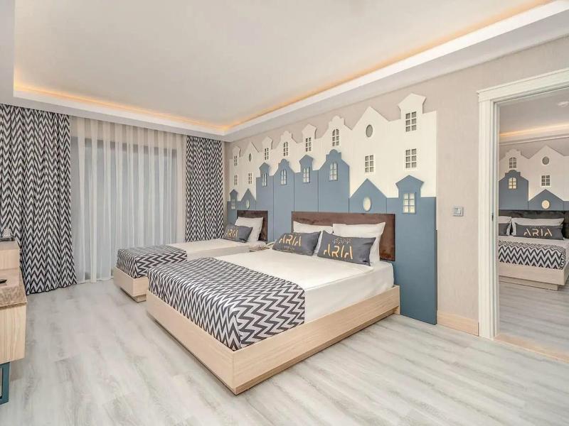 Chambre moderne avec grand lit, literie à motifs et mur décoré.
