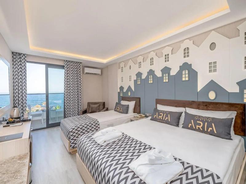 Chambre d'hôtel moderne avec vue sur la mer, deux lits simples et éclairage chaleureux.