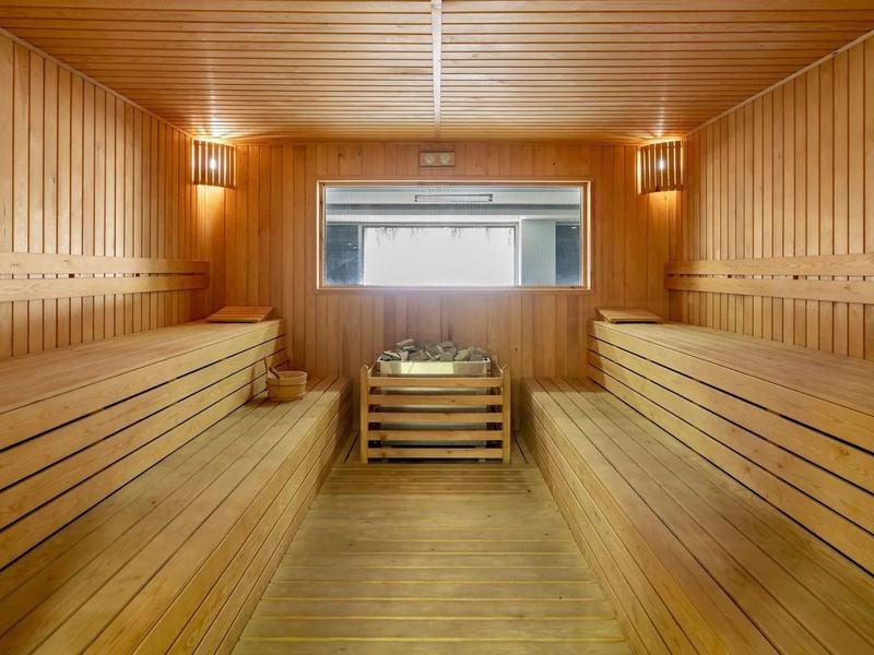 Grande sauna finlandaise avec boiseries, bancs et éclairage doux.
