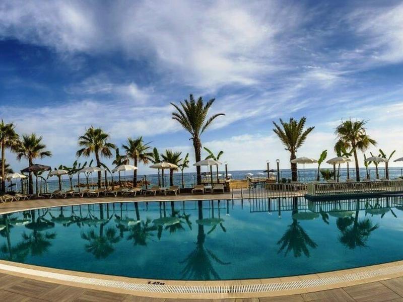 Piscine ronde avec des palmiers et un ciel bleu dans un complexe de luxe.