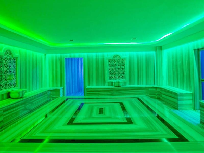 Hammam turc moderne avec éclairage LED vert et bancs en marbre