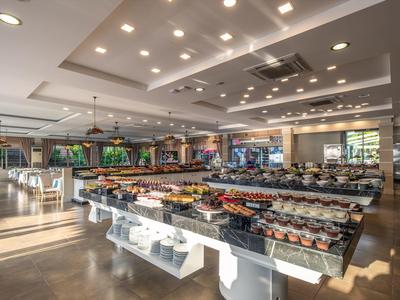 Großer, moderner Speisesaal mit Tischen, Stühlen und Buffetstationen in hellem Licht.