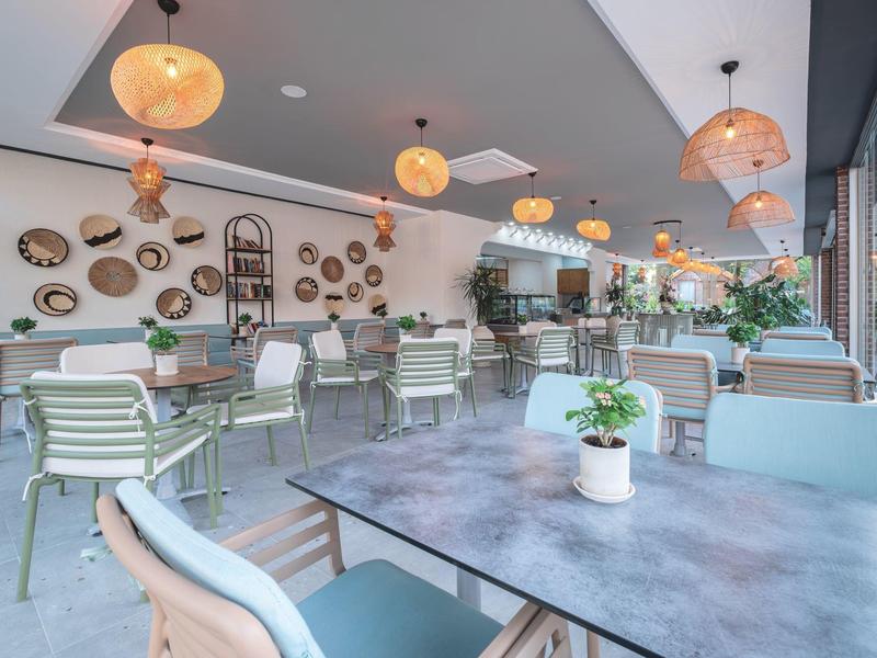 Moderne restaurantinrichting met tafels, stoelen, hanglampen en wanddecoraties.