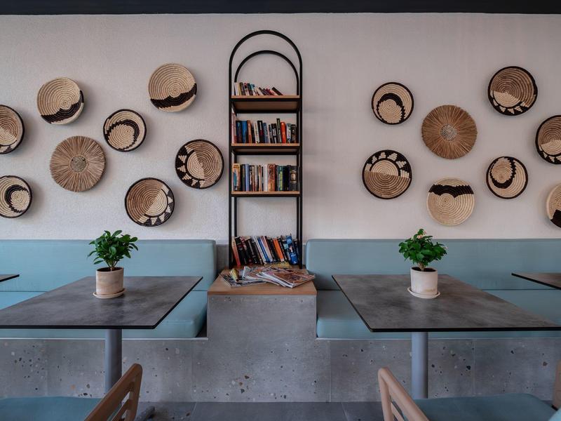 Gezellige eetruimte met houten tafels, planten en decoratieve hoeden aan de muur