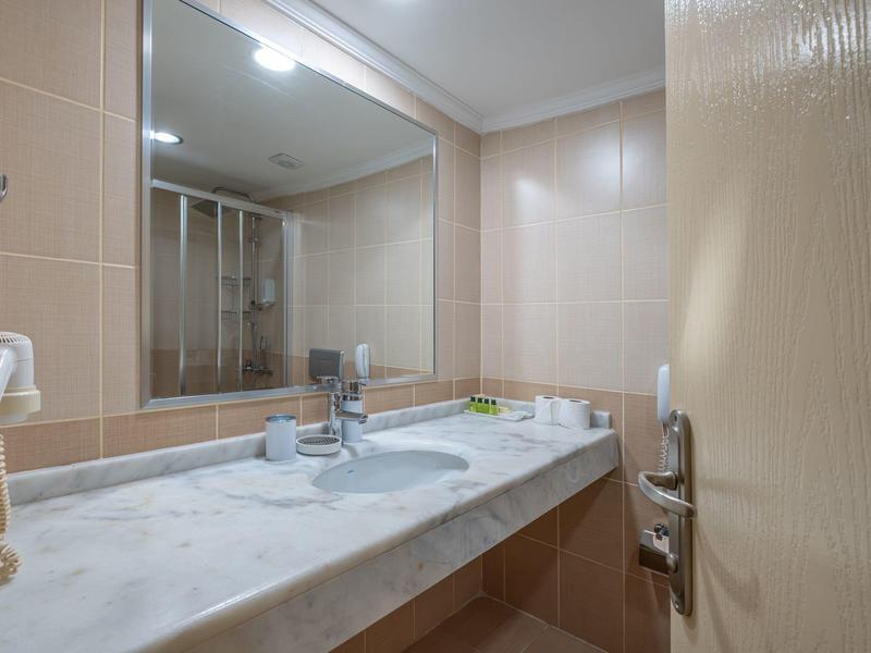 Moderne badkamer met marmeren wastafel, grote spiegel en glazen deur douche.