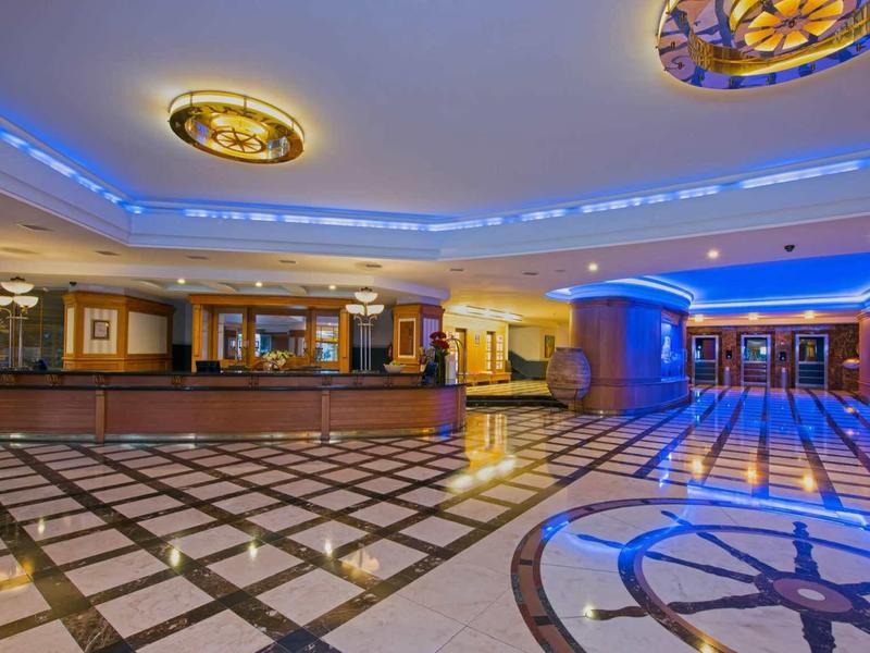 Ingresso ampio di hotel con pavimento in marmo e illuminazione blu.