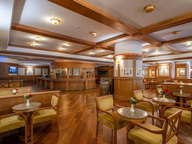 Salone dell'hotel luminoso con poltrone in legno e tavoli rotondi eleganti.