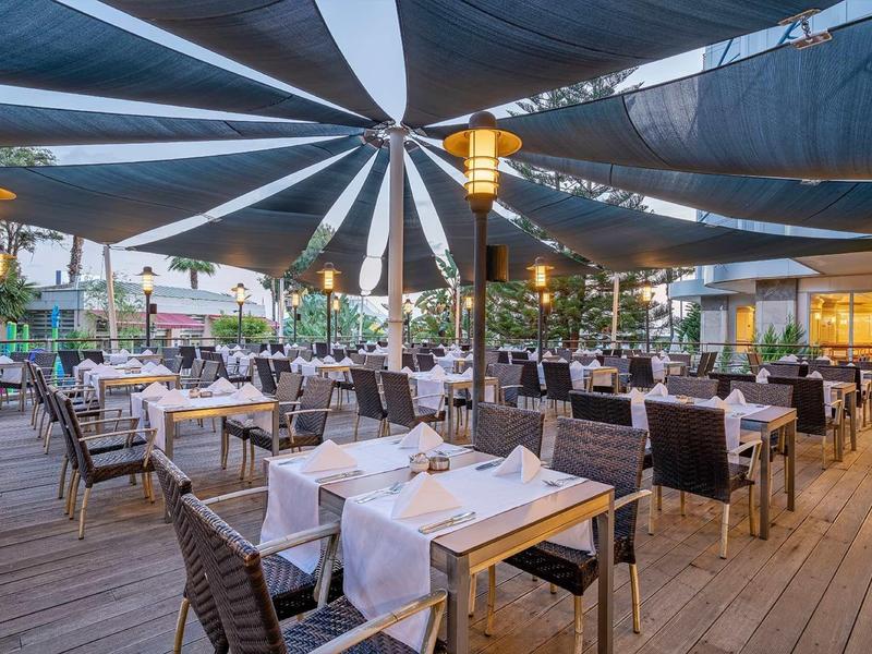 Ristorante all'aperto elegante con tavoli apparecchiati sotto una grande tenda ombreggiante.