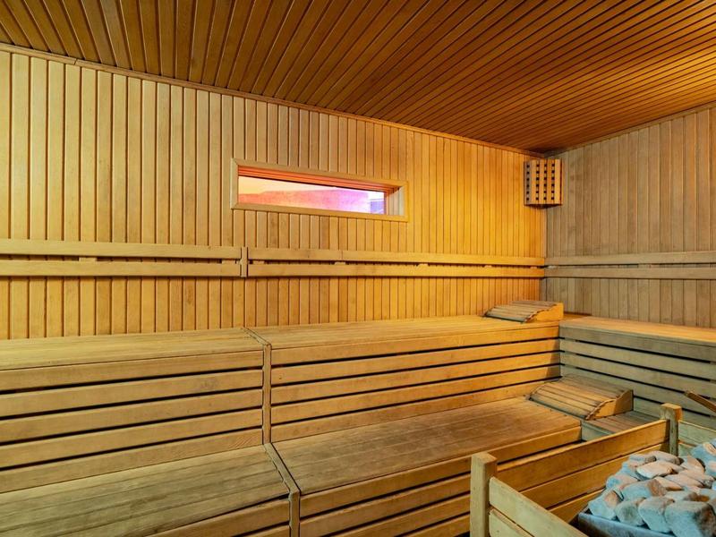 Interno accogliente di una sauna in legno con panche e una stufa a pietre.