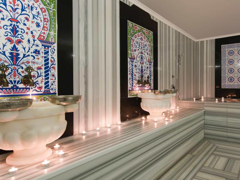 Bagno di lusso con vasca, candele e piastrelle grigie a strisce.