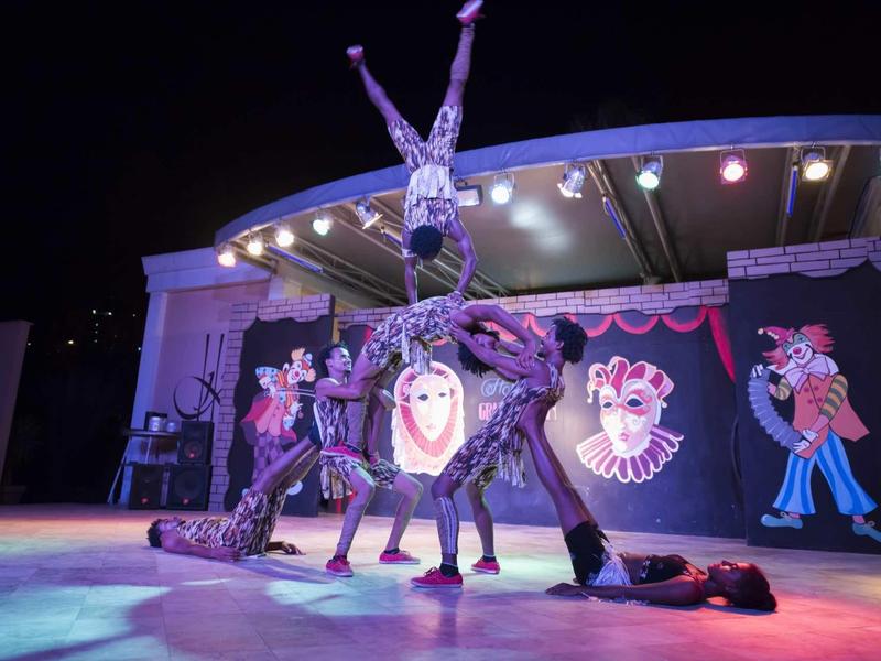 Spettacolo di circo con acrobata che tiene una posa sul palco illuminato.