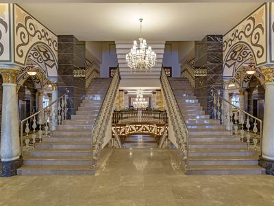 Atrio di hotel di lusso con grande scala in marmo e lampadario elegante.