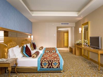 Camera d'hotel elegante con letto matrimoniale, TV, scrivania e decorazioni calde.