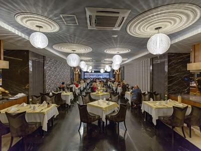 Sala da ristorante elegante con tavoli apparecchiati e luci rotonde sospese.