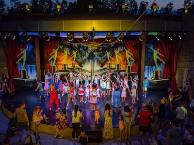 Palco colorato con artisti durante uno spettacolo serale all'aperto davanti al pubblico.